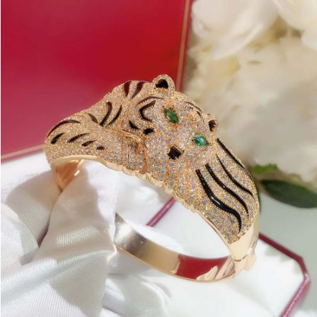 Gold tiger-shaped bracelet with gemstones on a white and red background