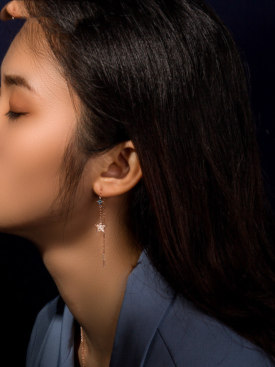 Close-up of a woman wearing a delicate earring with a dark background