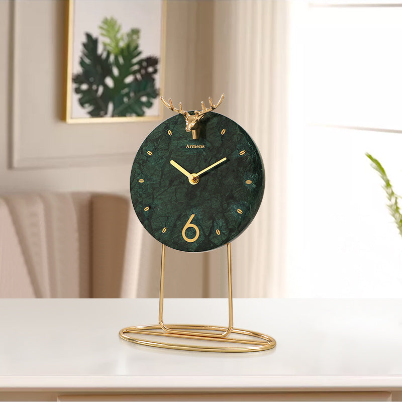 Decorative clock with gold stand on a white surface, blurred indoor background