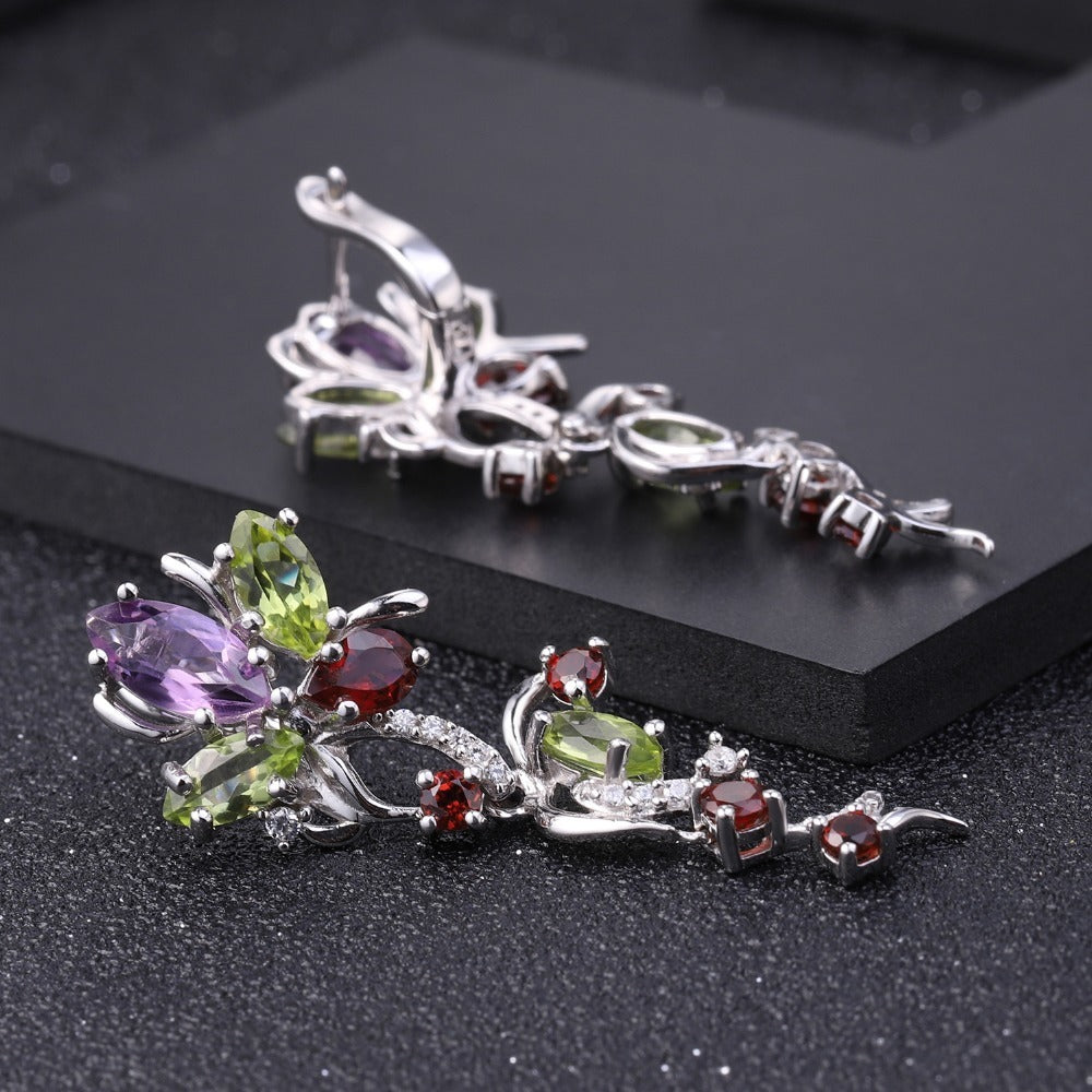 Pair of silver earrings with colorful gemstones on a black background