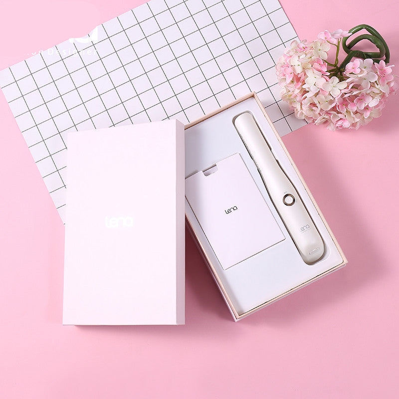 Product packaging with a white electronic device on a pink surface with flowers and grid paper.