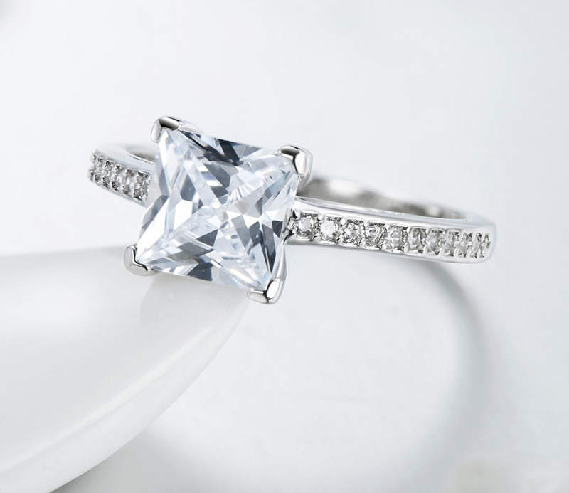 Diamond ring with a large central stone and smaller stones on the band against a white background
