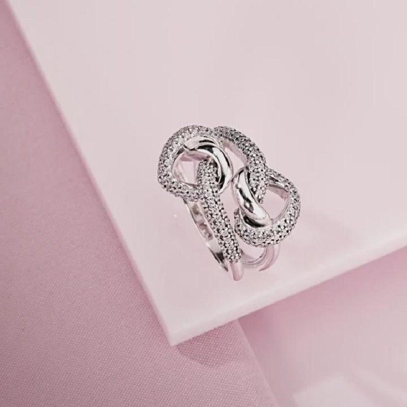 Silver ring with intricate design on a pink fabric background