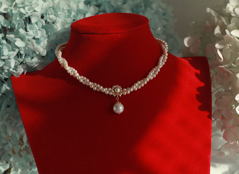 Pearl necklace on a red velvet stand with a floral background