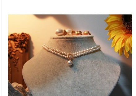 Pearl necklace on a mannequin with a sunflower in the background