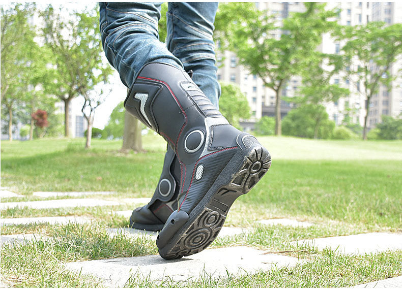 Person wearing black hiking boots with red accents walking on a paved path in a park.