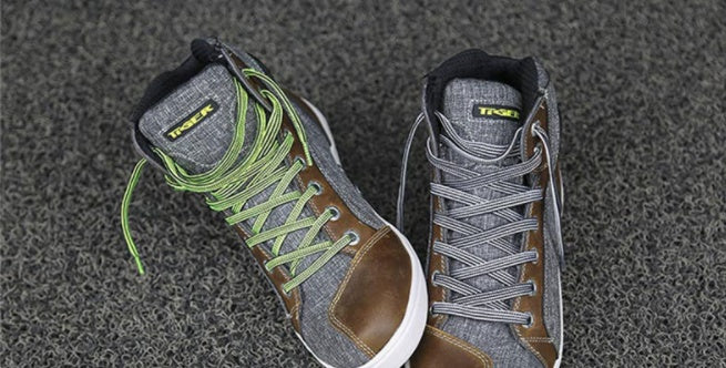 Pair of high-top sneakers with green laces on a textured gray surface