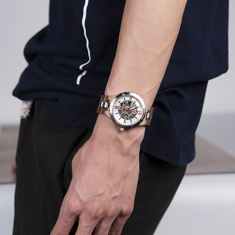 Person wearing a gold wristwatch with a white face on a neutral background