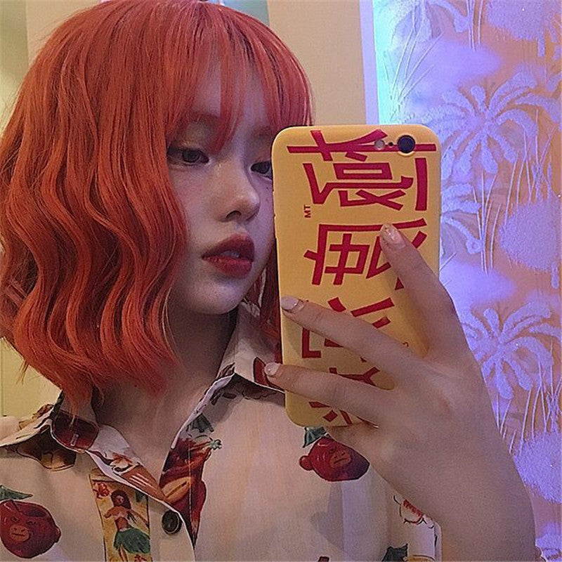 Person with red hair holding a phone with a yellow case featuring red text.