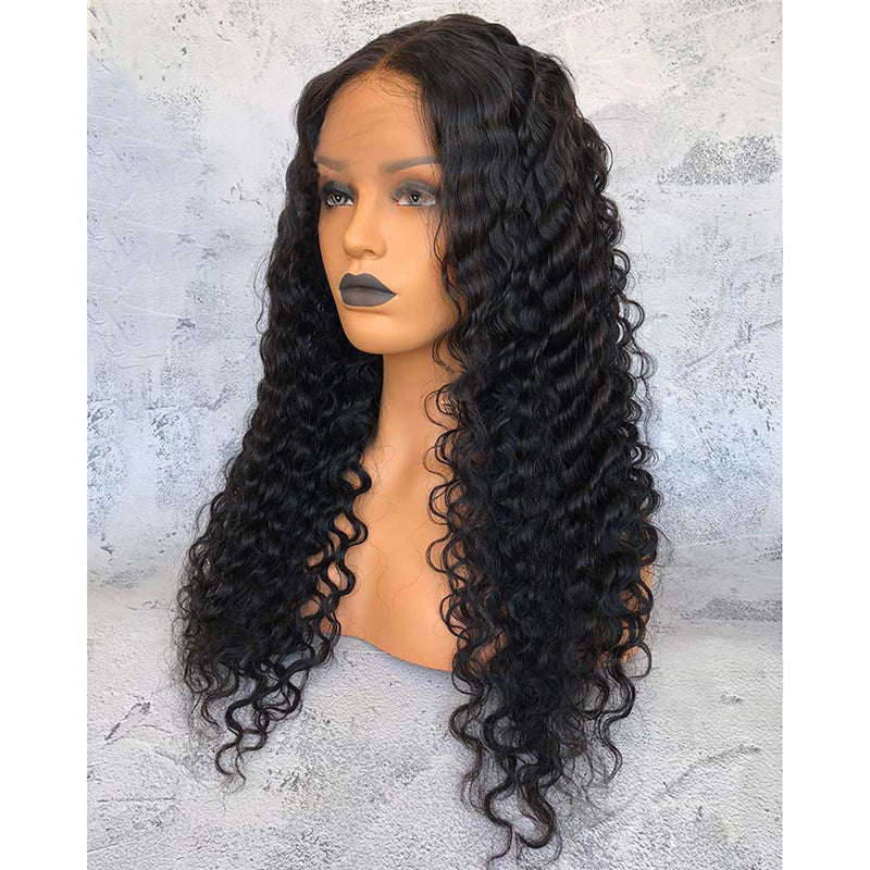Black curly wig on a mannequin head against a textured gray background