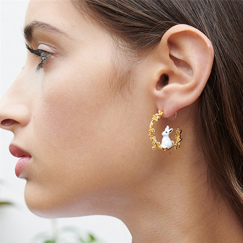 Close-up of a woman wearing a gold hoop earring with a rabbit design.
