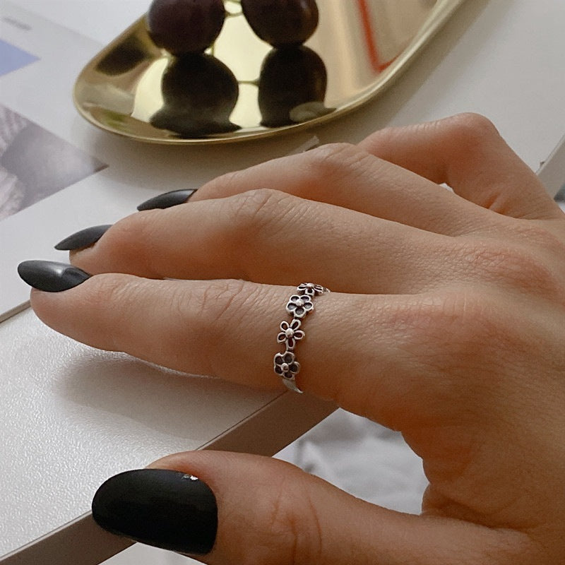 Hand wearing a silver ring with a decorative design on a blurred background