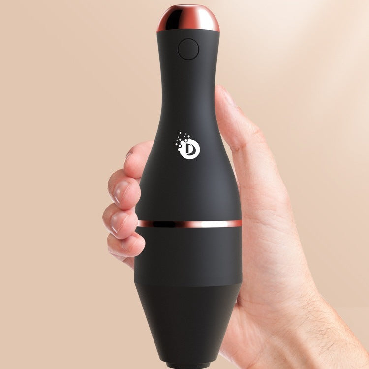 Black handheld device with rose gold accents held in a hand against a beige background