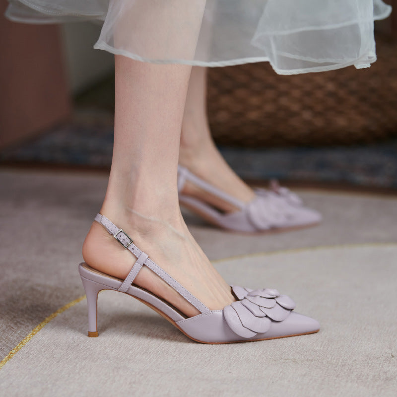Light purple high-heeled shoes with floral details worn by a person.