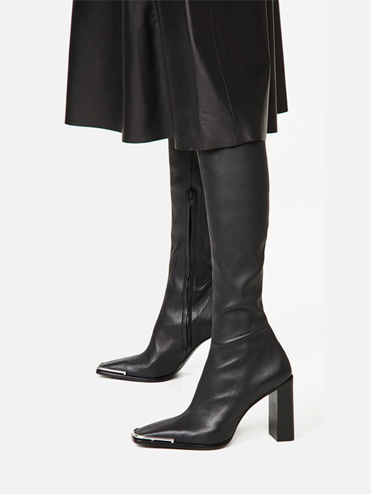 Black knee-high boots worn with a black coat on a white background