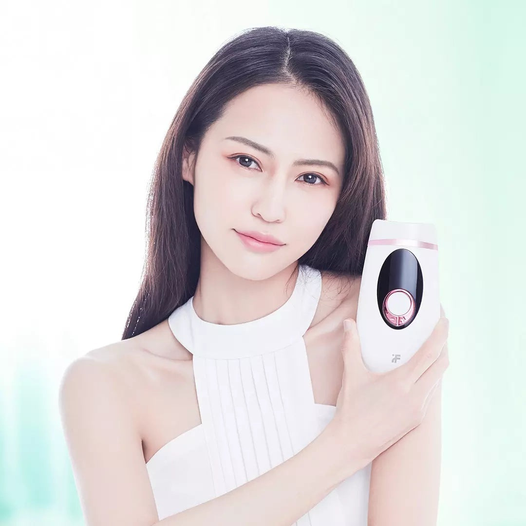 Woman holding a white electronic device with a pink accent on a light green background