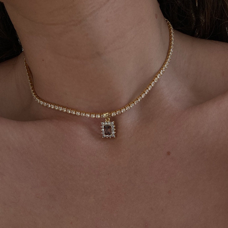 Gold necklace with a pendant on a person's neck