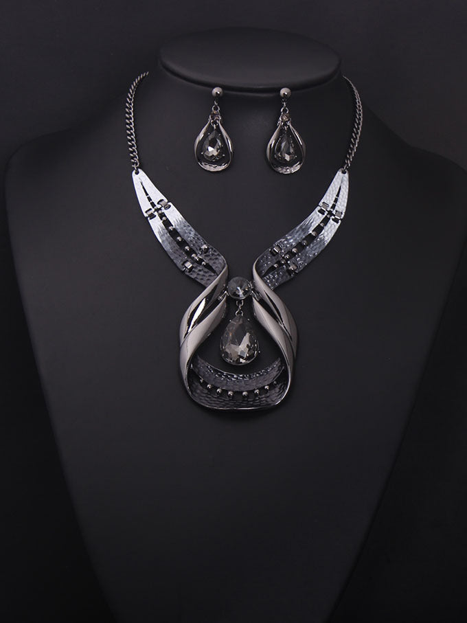 Silver necklace and earrings on a black background