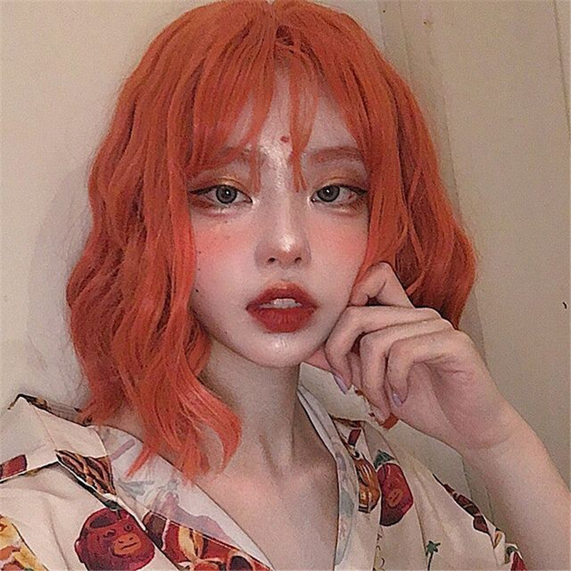 Person with bright orange hair wearing a patterned shirt against a neutral background