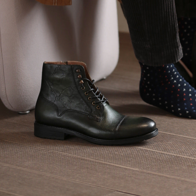 Black leather boot on a wooden floor with a suitcase in the background