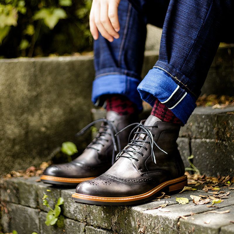 Person wearing dark brown leather shoes with brown soles, sitting on a stone ledge with a blurred natural background.