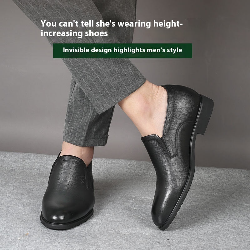 Black dress shoes worn with gray pants on a neutral background