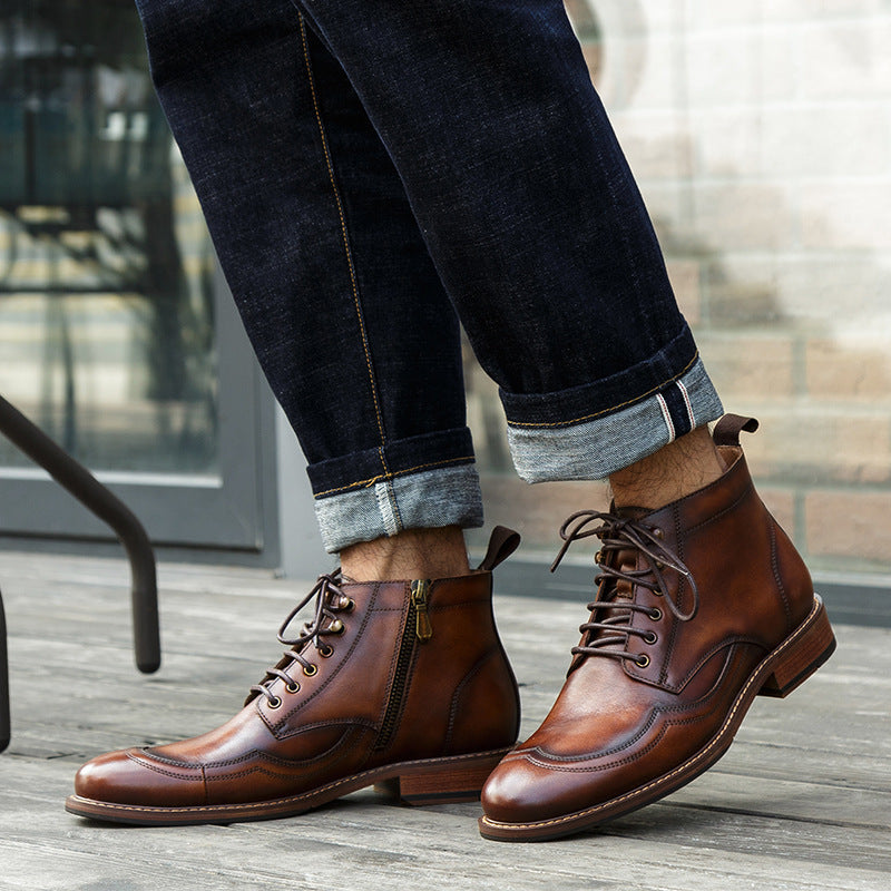 Brown leather boots worn with dark jeans on a wooden floor.