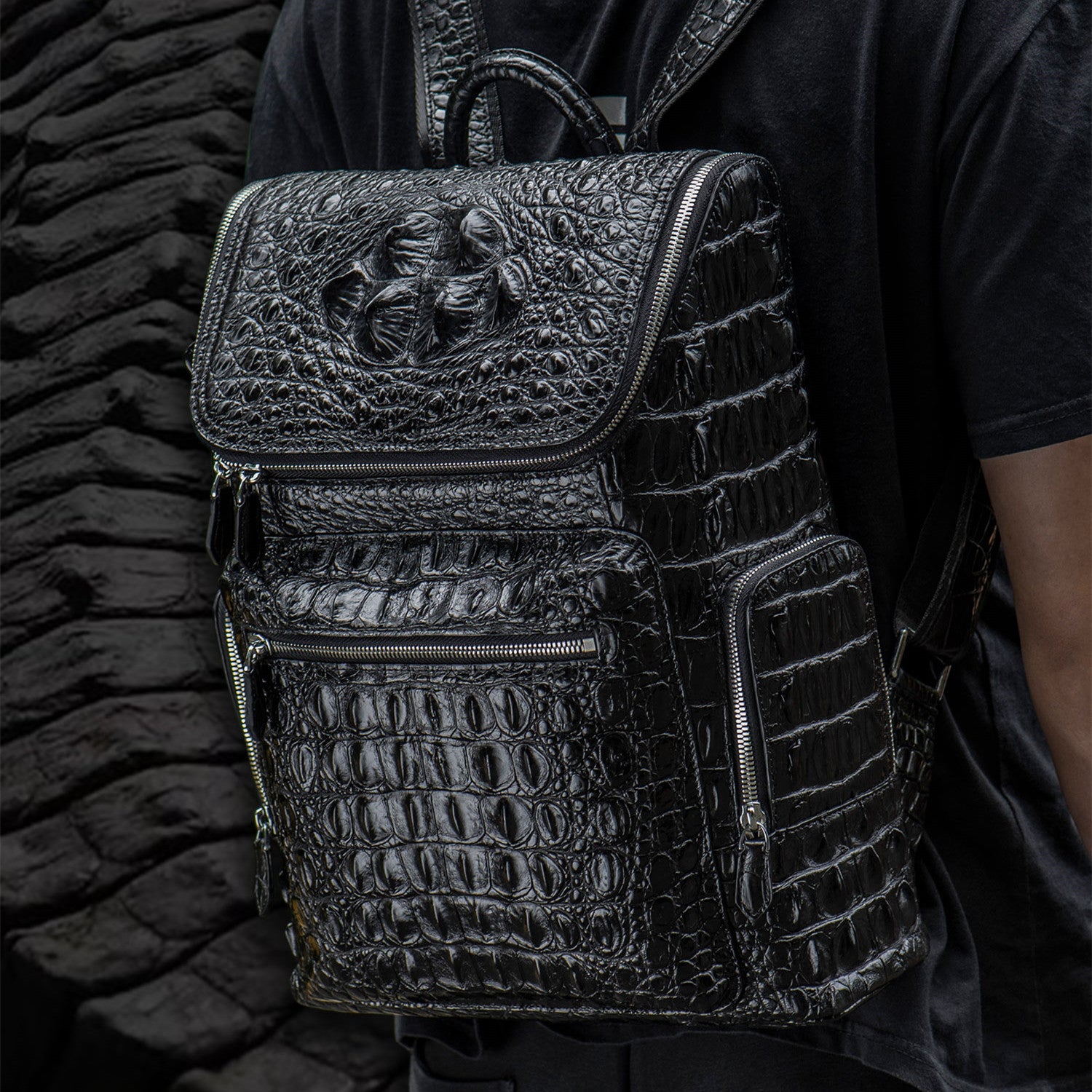 Black textured backpack worn by a person against a dark background