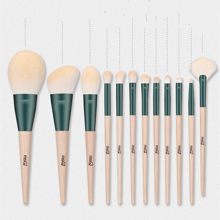 Set of makeup brushes with green handles and wooden shafts on a white background