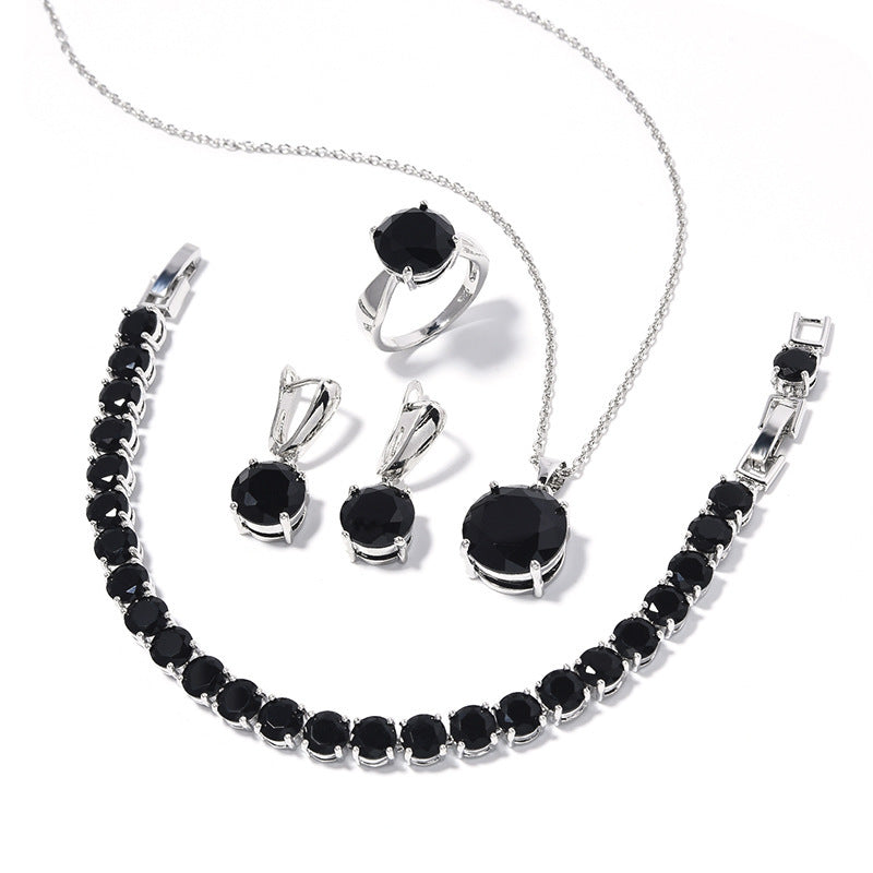 Jewelry set with necklace, bracelet, and earrings featuring black stones on a white background