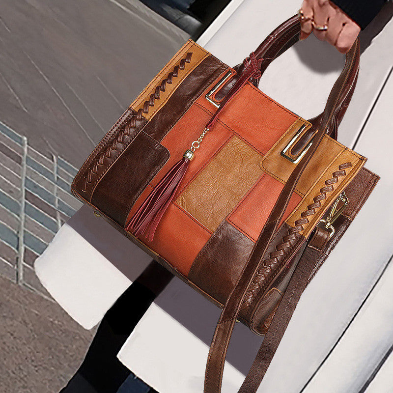 Brown and orange patchwork handbag with braided handles held by a person.