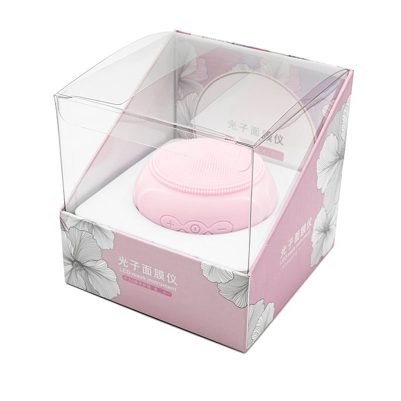 Pink facial mask device in a clear box with floral design on a white background