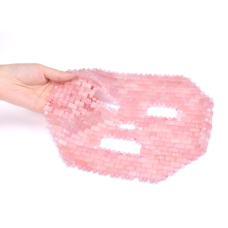 Pink beaded bag held by a hand on a white background