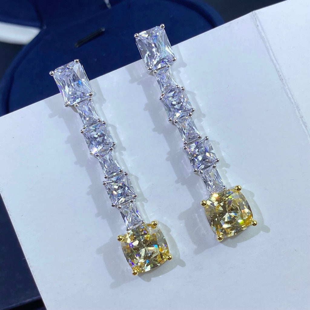 Pair of earrings with clear and yellow gemstones on a white surface