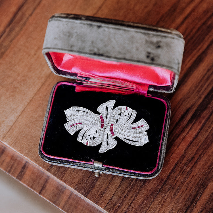 Diamond butterfly brooch in an open jewelry box on a wooden surface