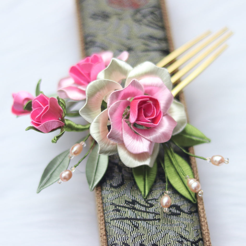 Floral hair comb with pink roses and green leaves on a white background