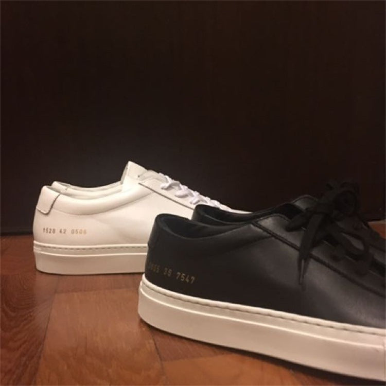 Pair of white and black sneakers on a wooden surface with a dark background