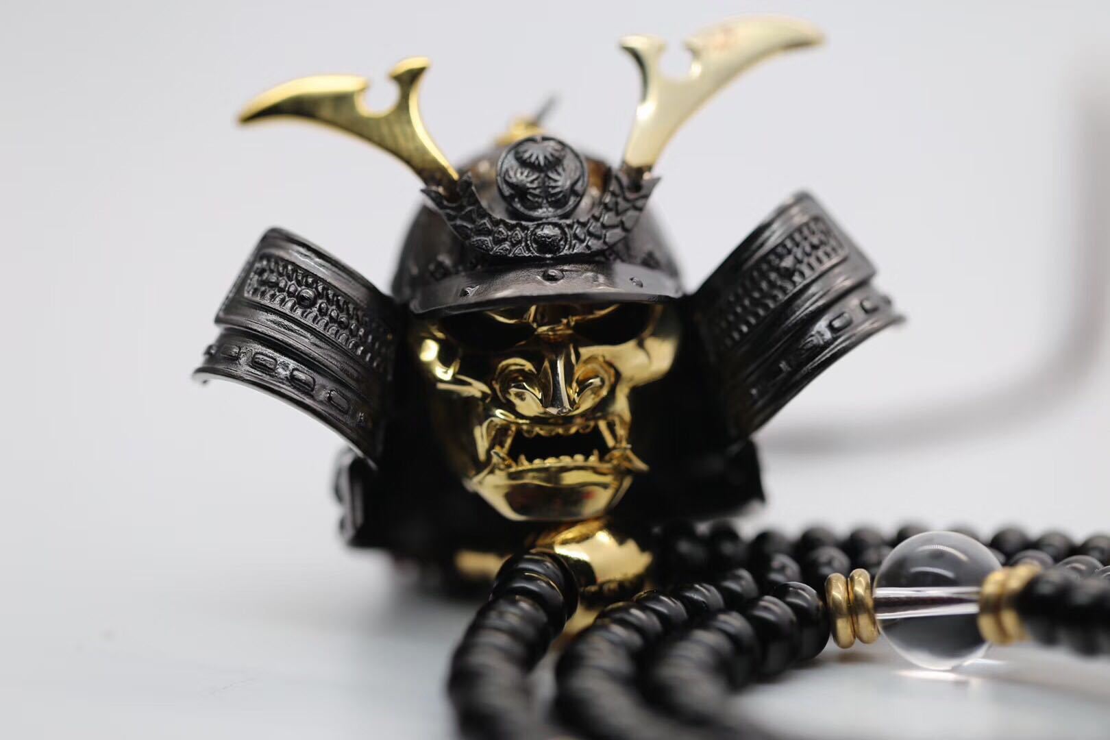 Gold and black samurai helmet pendant on a white background