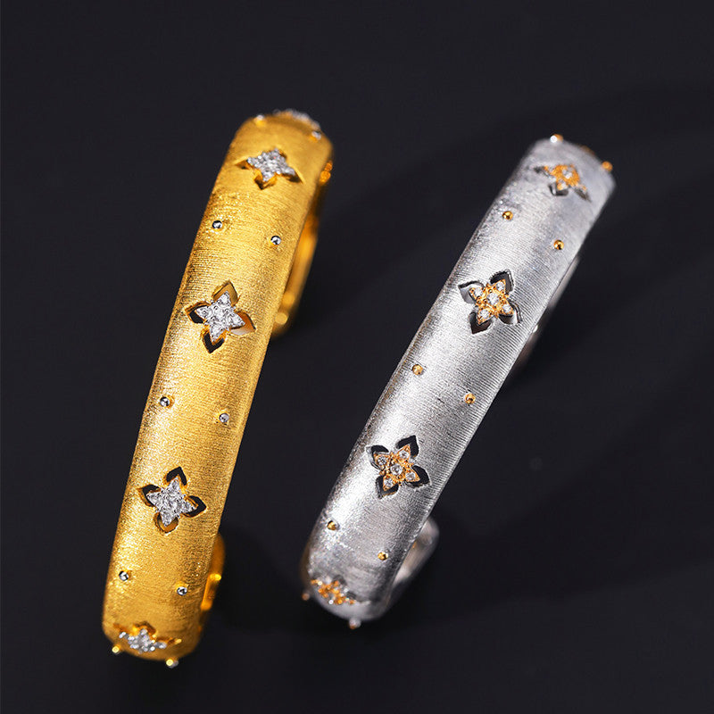 Gold and silver bangles with star designs on a black background