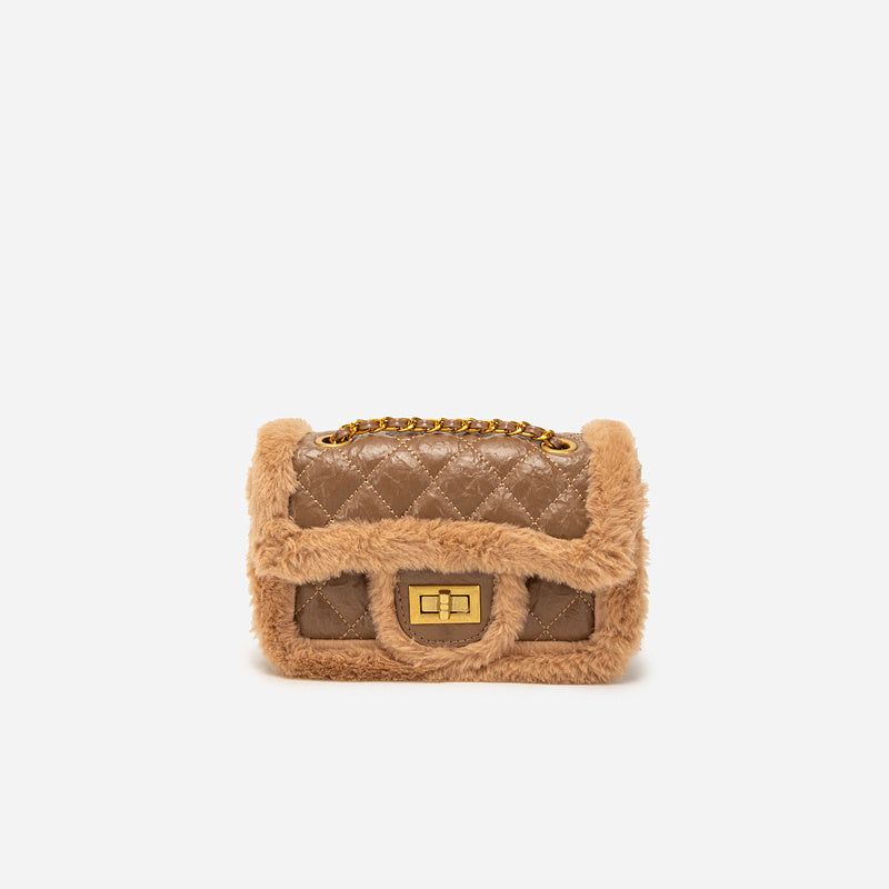 Quilted handbag with fur trim on a white background