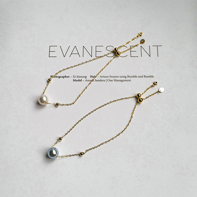 Gold necklace with pearls on a light gray background, featuring the brand 'Evanescence'.
