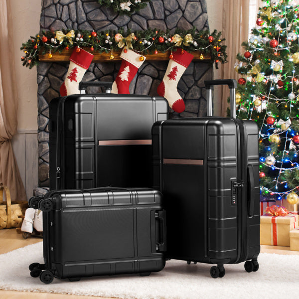 Black suitcases in front of a decorated fireplace and Christmas tree.