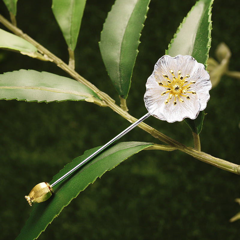 Floral brooch with a gold base on a green leaf background