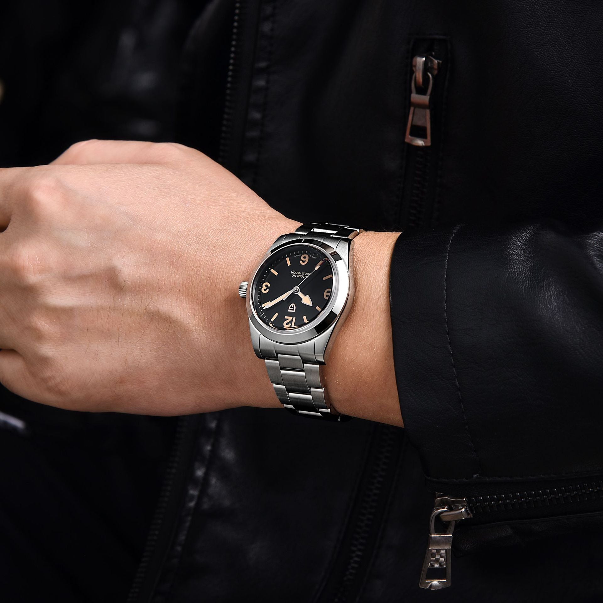 Silver watch on a person's wrist with a black jacket background
