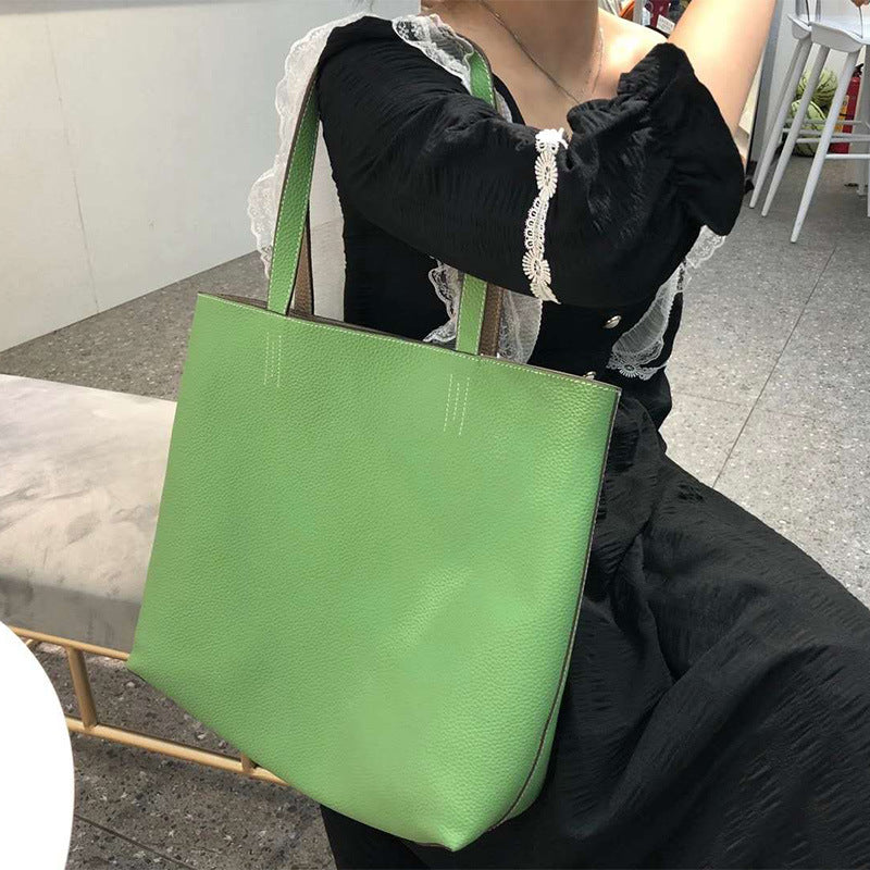 Person holding a green tote bag in an indoor setting