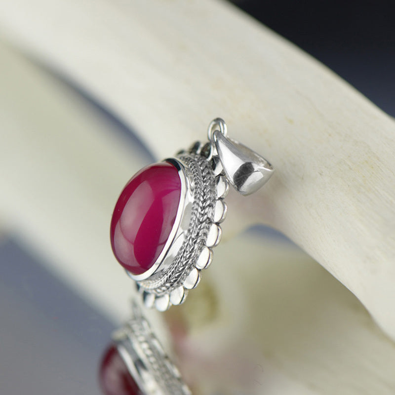 Silver pendant with a red gemstone on a white background