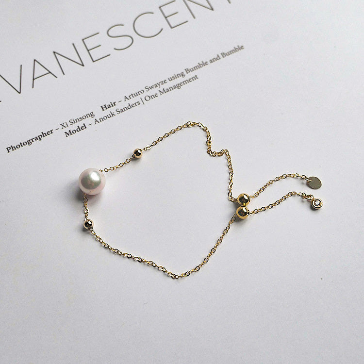 Gold bracelet with a pearl on a light gray background