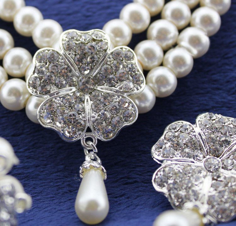 Pearl necklace with silver floral clasp on a blue background