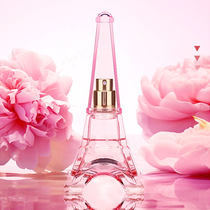 Pink Eiffel Tower-shaped perfume bottle with pink flowers in the background