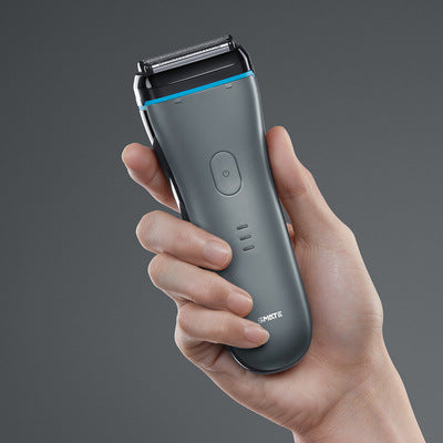 Hand holding a gray electric shaver with a blurred gray background